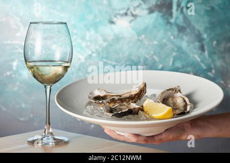 Austern in einem weißen Teller mit Zitrone Stockfoto