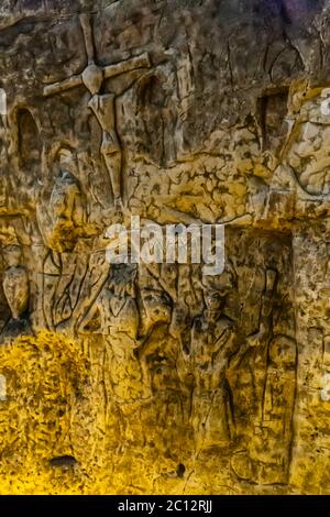 Die Royston Cave in Herfordshire, Großbritannien, verwirrt heute noch Historiker. Die Höhle ist mit einer großen Anzahl von Wandskulpturen mit niedrigem Relief dekoriert. Es sind hauptsächlich christliche Motive im mittelalterlichen Stil. Oben links ist eine Kreuzigung dargestellt. Royston Cave in Katherine's Yard, Melbourn Street, Royston, England Stockfoto