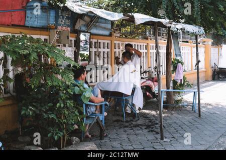 Street Barber arbeitet an einem Kunden in Phnom Penh Kambodscha Stockfoto