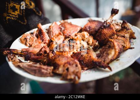 Hand des Mannes hält gegrilltes Brathähnchen auf weißen Teller Stockfoto