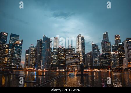 Abendfoto des beleuchteten Geschäftsviertels von Singapur, das sich in der Abenddämmerung im Wasser der Bucht widerspiegelt Stockfoto