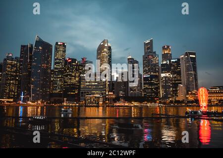 Abendfoto des siluminierten Geschäftsviertels von Singapur, das sich im Wasser der Bucht widerspiegelt Stockfoto