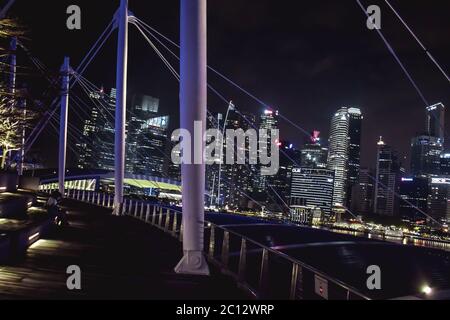 Beleuchtete Skyline von Singapur vom Dach der Marina Bay Mall in der Nacht Stockfoto