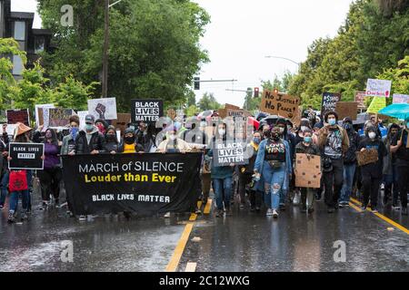 Black Lives Matter Chair, EBONY MIRANDA, (in gelb) führt Unterstützer in einem stillen marsch durch den Central District von Seattle am Freitag, den 12. Juni 2020. Tausende von Unterstützern trotzten heftigen Regenfällen, um an dem landesweiten Schweigemmarsch und dem Generalstreik teilzunehmen. Black Lives Matter Seattle-King County organisierte den landesweiten Aktionstag und einen stillen marsch, um die verlorenen Leben zur Unterstützung aller Schwarzen im Staat Washington zu ehren. Stockfoto