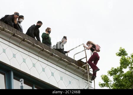 Eine junge Frau steigt am Freitag, den 12. Juni 2020, auf die Feuerstelle des Kelly-Springfield Motor Truck Building, um auf das Dach der „Autonomen Zone Capitol Hill“ in Seattle zu gelangen. Die Zone, auch bekannt als CHAZ, ist eine selbsterklärte, absichtliche Gemeinde und Kommune, die gegründet wurde, als die Polizeibehörde von Seattle das East Precinct nach tagelang großen Protesten und gelegentlichen gewalttätigen Zusammenstößen schloss. Stockfoto