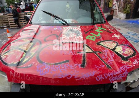 Ein Auto mit Graffiti geschmückt ist in der "Capitol Hill Autonomous Zone" in Seattle am Freitag, 12. Juni 2020 geparkt. Die Zone, auch bekannt als CHAZ, ist eine selbsterklärte, absichtliche Gemeinde und Kommune, die gegründet wurde, als die Polizeibehörde von Seattle das East Precinct nach tagelang großen Protesten und gelegentlichen gewalttätigen Zusammenstößen schloss. Stockfoto