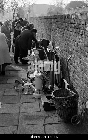 AJAXNETPHOTO. FEBRUAR 1975. PORTSMOUTH, ENGLAND. - FLOHMARKT - IN DER UNICORN ROAD; KÄUFER STÖBERN DURCH GEBRAUCHTE WAREN UND KLEIDUNG AUF DEM BÜRGERSTEIG.FOTO:JONATHAN EASTLAND/AJAX REF:7513 4 123 Stockfoto