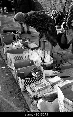 AJAXNETPHOTO. FEBRUAR 1975. PORTSMOUTH, ENGLAND. - FLOHMARKT - IN DER UNICORN ROAD; KÄUFER STÖBERN DURCH GEBRAUCHTE WAREN UND KLEIDUNG AUF DEM BÜRGERSTEIG.FOTO:JONATHAN EASTLAND/AJAX REF:7513 16 132 Stockfoto