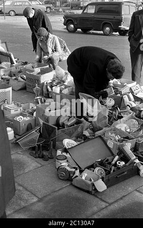 AJAXNETPHOTO. FEBRUAR 1975. PORTSMOUTH, ENGLAND. - FLOHMARKT - IN DER UNICORN ROAD; KÄUFER STÖBERN DURCH GEBRAUCHTE WAREN UND KLEIDUNG AUF DEM BÜRGERSTEIG.FOTO:JONATHAN EASTLAND/AJAX REF:7513 19 134 Stockfoto