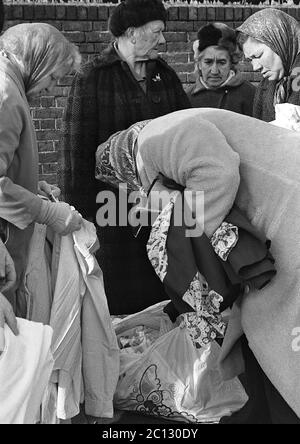 AJAXNETPHOTO. FEBRUAR 1975. PORTSMOUTH, ENGLAND. - FLOHMARKT - IN DER UNICORN ROAD; KÄUFER STÖBERN DURCH GEBRAUCHTE WAREN UND KLEIDUNG AUF DEM BÜRGERSTEIG.FOTO:JONATHAN EASTLAND/AJAX REF:7513 27 135 Stockfoto