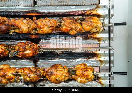 Hühner auf einer Rotisserie auf einem Markt braten Stockfoto