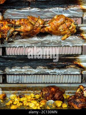Hühner auf einer Rotisserie auf einem Markt braten Stockfoto