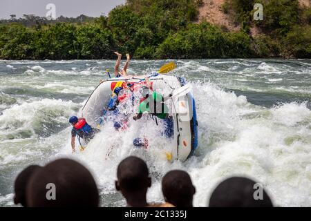 Zuschauer beobachten, wie ein Wasserfloß bei einer Wildwasser-Rafting-Expedition auf dem Nil in der Nähe von Jinja, Uganda, Afrika, kentert Stockfoto