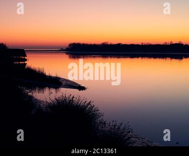 Sonnenuntergang von Caorle, Venedig: Wunderschöne Farben des Winteruntergangs in Caorle mit Blick auf die Madonnina dell'Angelo von der venezianischen Lagune in Brussa Stockfoto