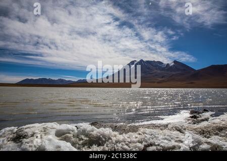 see Abtauen in der Wüste von bolivien mit einem Vulkan im Hintergrund Stockfoto