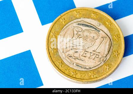 Schmutzige Griechenland-Euro-Münze gelegt auf die Griechenland-Flagge Stockfoto