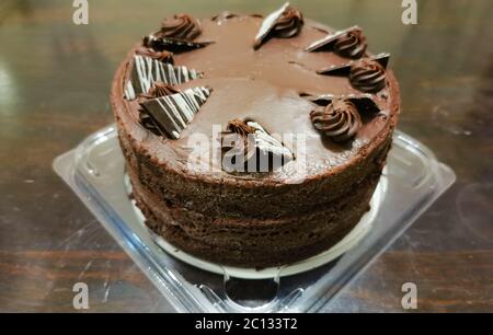 Ein dreilagiger feuchter Schokoladenkuchen mit Butterschokolade-Glasur und mit Ganache und Choc-Dreiecken Stockfoto