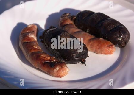 Gericht mit verschiedenen Würstchen, Blutwurst und Würstchen, gegrillt während eines Grills auf dem Land Stockfoto