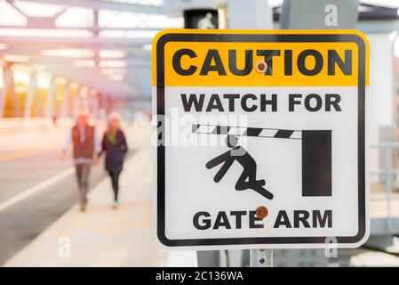 Schild entlang eines Gehwegs auf einer vertikalen Hubbrücke warnt Fußgänger vor einem beweglichen Torarm Stockfoto