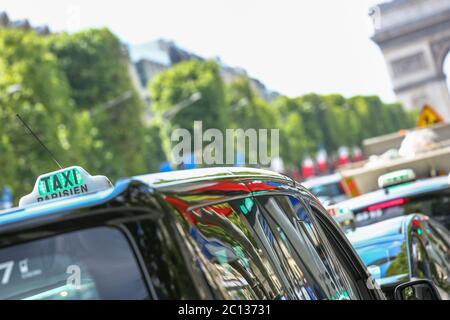 Pariser Taxi auf der Avenue des champs-elysees, mit dem Arc de Triomphe und Verkehr im Hintergrund Stockfoto