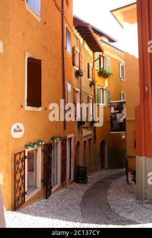 Enge gepflasterte Straße zwischen alten Gebäuden in Malcesine, Italien Stockfoto