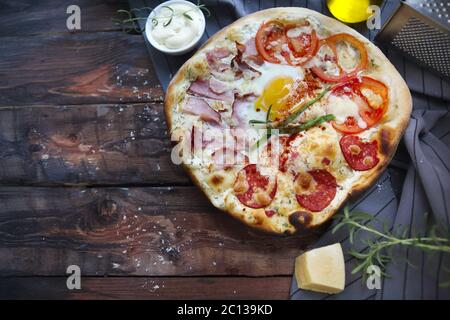 Pizza Carbonara mit Speck, Salami, Parmesan und Hühnereier Stockfoto