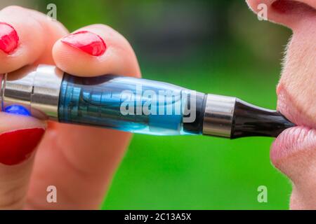 Eine Frau, die aus einer elektronischen Zigarette inhaliert Stockfoto