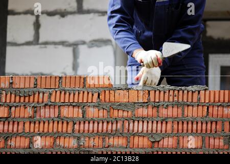 Professionelle Bauarbeiter legen Ziegelsteine und Hausbau auf Industriegelände Stockfoto