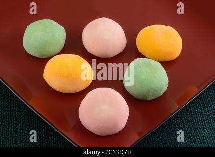 Erdbeer, grüner Tee und Mango-Eis Mochi Kugeln auf roten Dessert-Platte Stockfoto