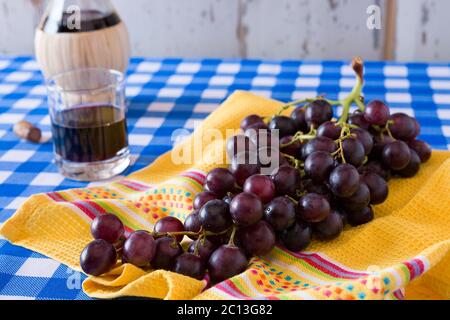 Nahaufnahme eines Bündels von roten Trauben und einem Glas Rotwein Stockfoto