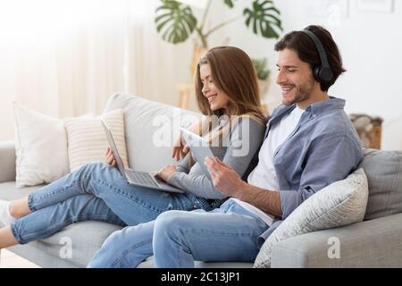 Paar sitzt auf der Couch zu Hause und mit Gadgets Stockfoto