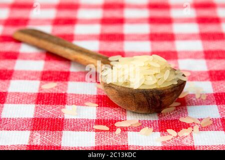 Roher, parboiled Reis in einem Holzlöffel Stockfoto