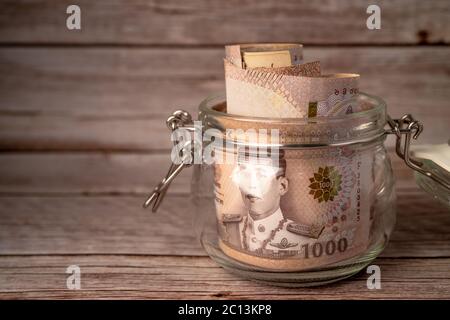 Thai Baht Banknoten in Gras Glas auf Holzhintergrund, Business-Sparen Finanzierung Investitionskonzept. Stockfoto