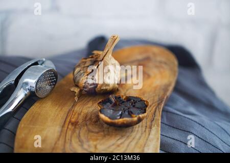 Schwarzer Knoblauch Zwiebeln und Knoblauchzehen auf hölzernen Hintergrund Stockfoto