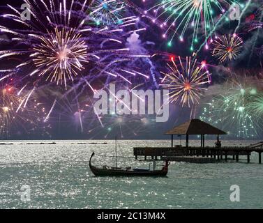 Festliches Feuerwerk über dem Meer und eine Schiffssilhouette auf dem Wasser. Malediven. Stockfoto