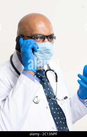 Indische männliche Arzt unterstützt Patienten online mit Telefon und Computer Während dieser Pandemie Stockfoto