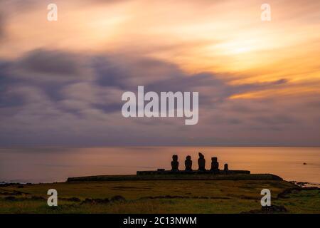 Langzeitbelichtung bei Sonnenuntergang mit Moai Statuen Silhouette und dem Pazifik bei Ahu Tahai in der Nähe von Hanga Roa Dorf, Rapa Nui (osterinsel), Chile. Stockfoto