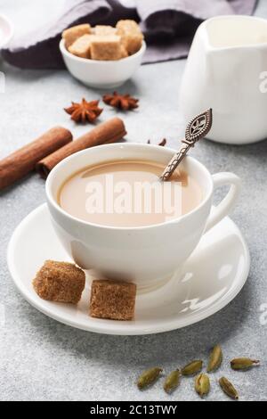 Indischer Tee mit Milch und Gewürzen. Kardamom Sticks Zimt Stern Anis Rohrzucker Stockfoto