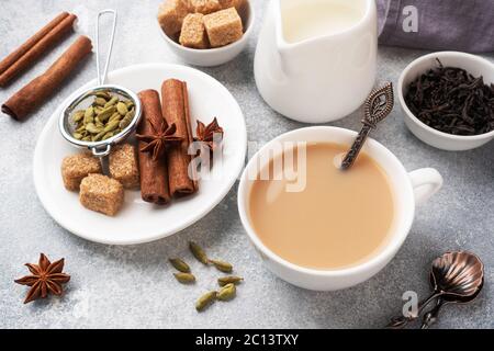 Indischer Tee mit Milch und Gewürzen. Kardamom Sticks Zimt Stern Anis Rohrzucker Stockfoto