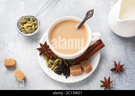 Indischer Tee mit Milch und Gewürzen. Kardamom Sticks Zimt Stern Anis Rohrzucker Stockfoto