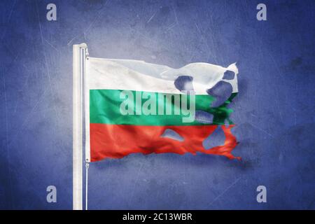 Zerrissene Flagge Bulgariens, die vor grunge Hintergrund fliegt Stockfoto