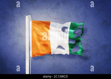 Zerrissene Flagge der Elfenbeinküste, die vor grunge Hintergrund fliegt Stockfoto