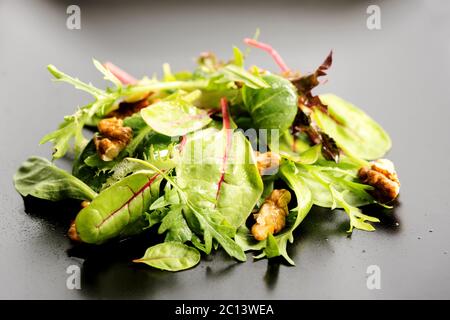 Salat mit Rucola, Frisee, Radicchio, Kopfsalat und Nüssen auf Teller mischen Stockfoto