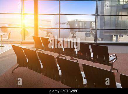 Leere Sessel im Saal der Erwartung des Flughafen und Flugzeug hinter Fenster Stockfoto