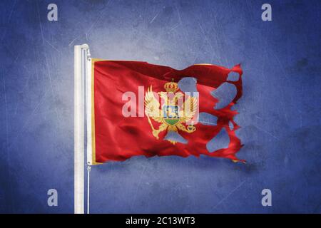Zerrissene Flagge Montenegros, die vor grunge Hintergrund fliegt Stockfoto
