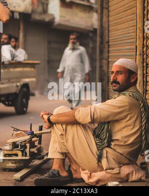 Karachi Pakistan 2018, eine Arbeit, die am Straßenrand sitzt und auf Kunden in der Morgenzeit wartet Stockfoto