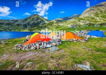 Bergcampingplatz mit bunten Zelten am Ufer des Bucura Sees. Wilder Zeltplatz in den Bergen mit schönem See, Retezat Berge, Karpaten Stockfoto