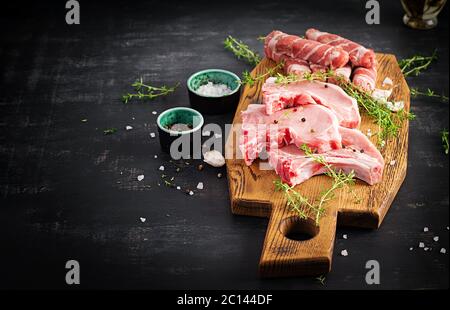 Rohe Schweinesteaks. Verschiedene Arten von rohem Schweinefleisch und gehackte Würstchen оn den dunklen Tisch. Speicherplatz kopieren Stockfoto