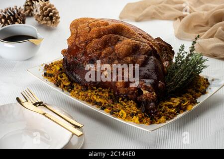 Gebratenes Schweineschulterschinken-Fleisch auf einer weißen Platte mit Geschirr Serviette und Kiefern Stockfoto