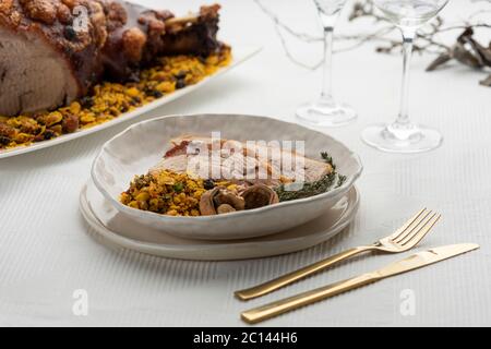 Gebratener Schweineschulterschinken mit Nüssen auf einem weißen Gericht und Speisen auf dem Hintergrund Stockfoto
